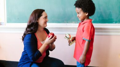 a teacher looking at her student while holding an apple
