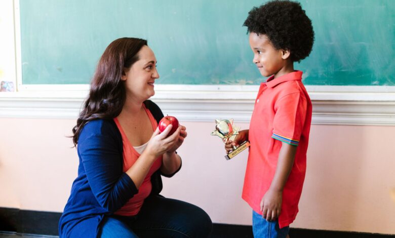 a teacher looking at her student while holding an apple